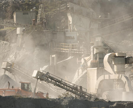 Gravel quarry at work. Stone crushing and screening machinery in clouds of dust